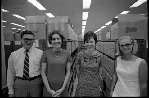 4 archivists standing in front of records boxes